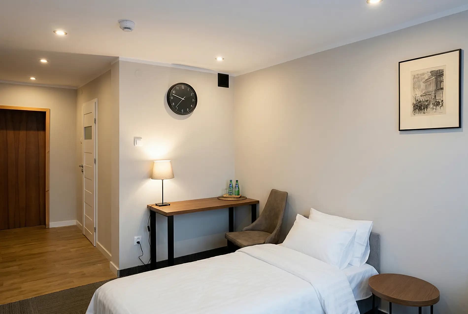 Komfortowy pokój noclegowy z biurkiem, zegarem i lampką