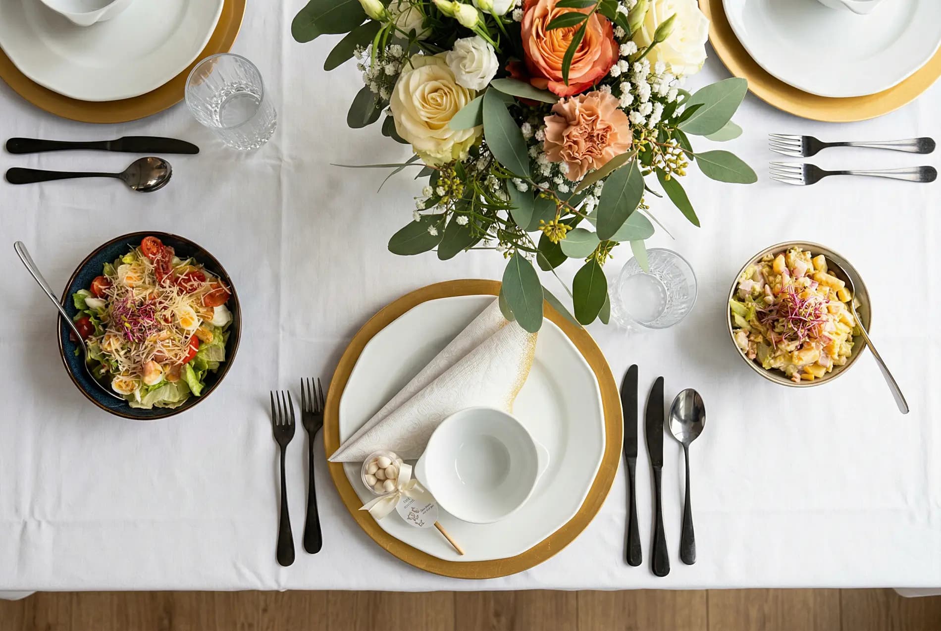 Elegancko nakryty stół — sałatki, kwiaty i złote talerze z profesjonalnego cateringu